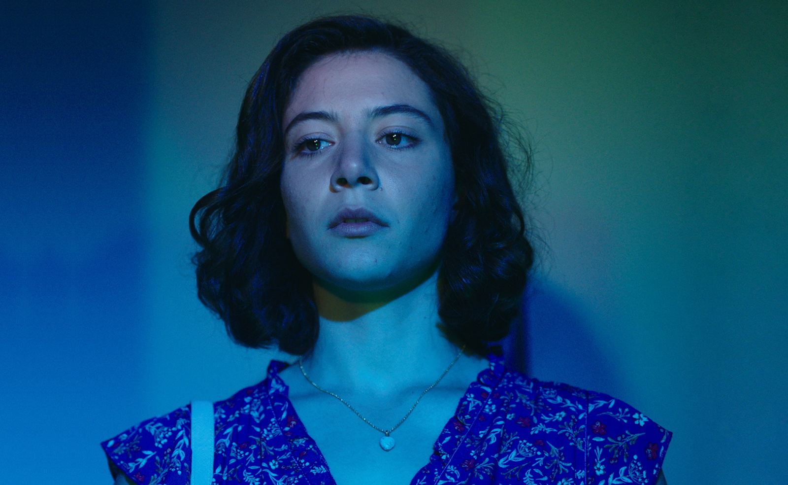 A woman in blue light looking into the camera